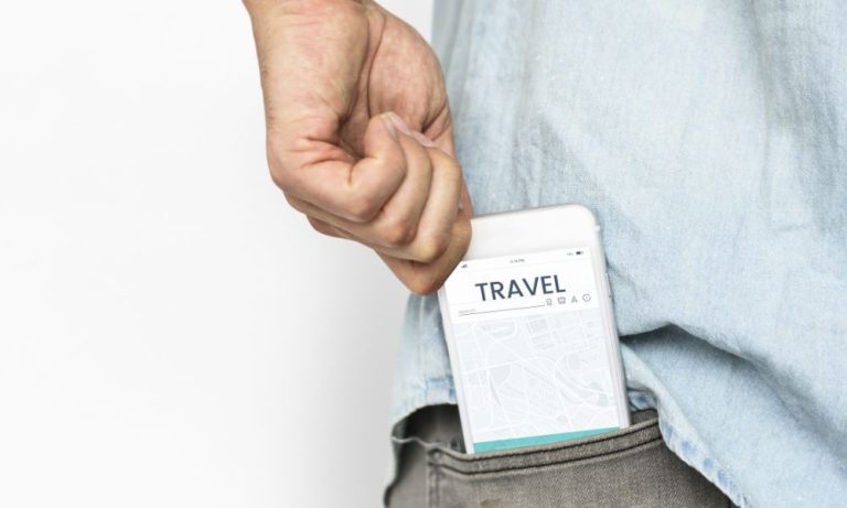 Hand placing smartphone with travel app into pocket